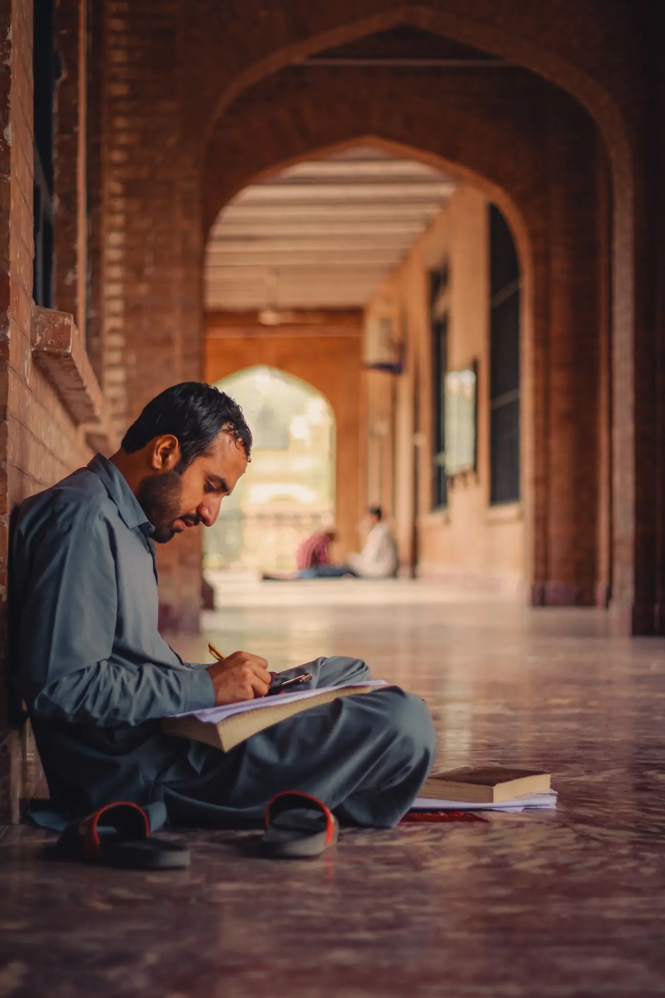 A student reading quietly in the arched corridor of a historic college